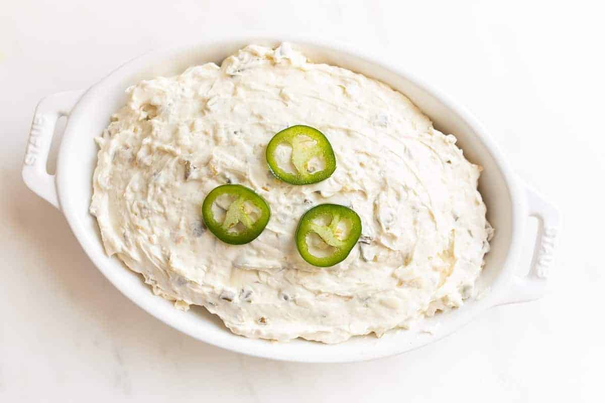 jalapeno cheese dip topped with fresh jalapenos in casserole dish just before baking