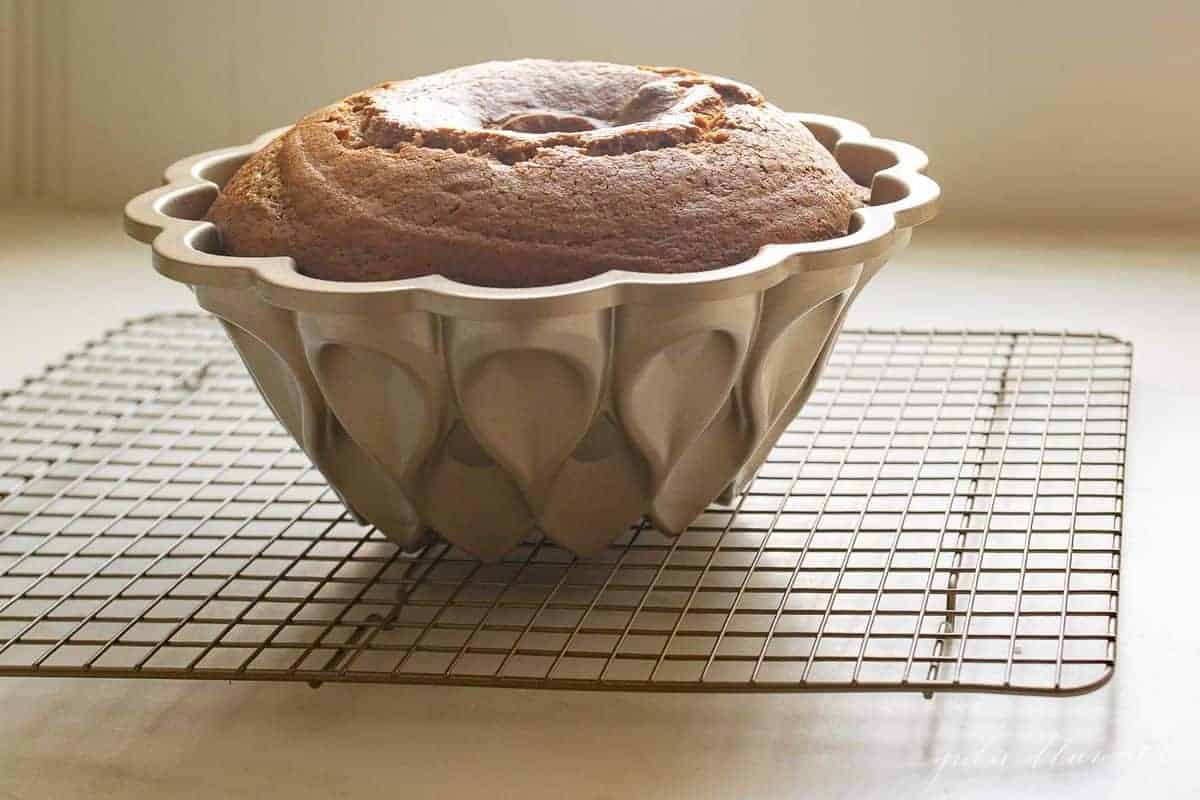 Metal bundt cake pan with a cake inside, placed on a metal baking rack.