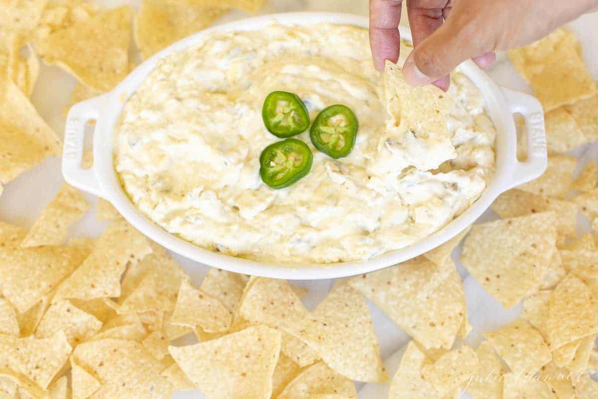 dipping a chip into creamy jalapeno dip