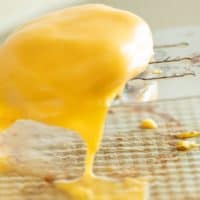 A burger patty covered in cheese, raising off a baking sheet with a metal spatula.