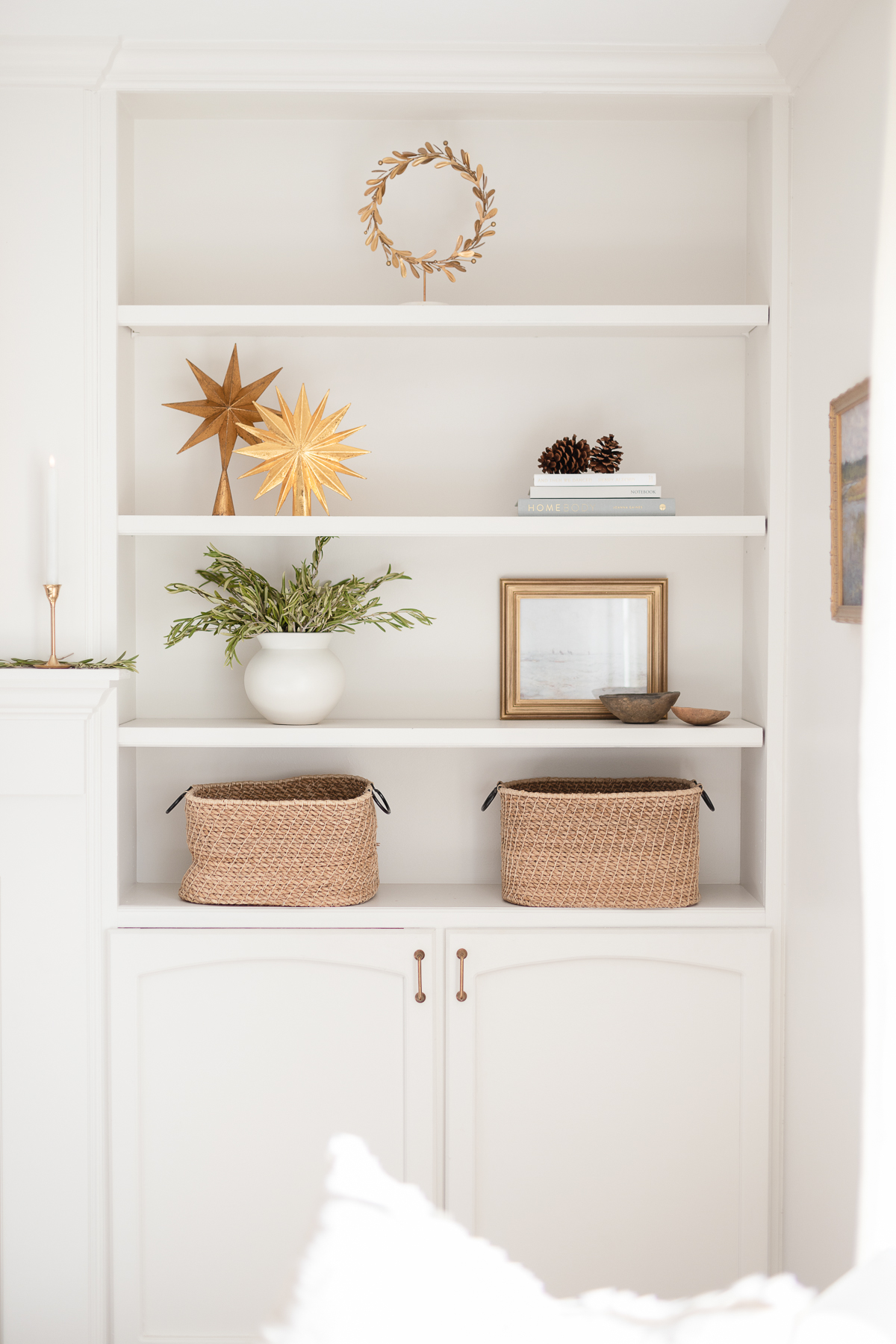 A white shelf with baskets and a fireplace adorned with laurel wreaths.