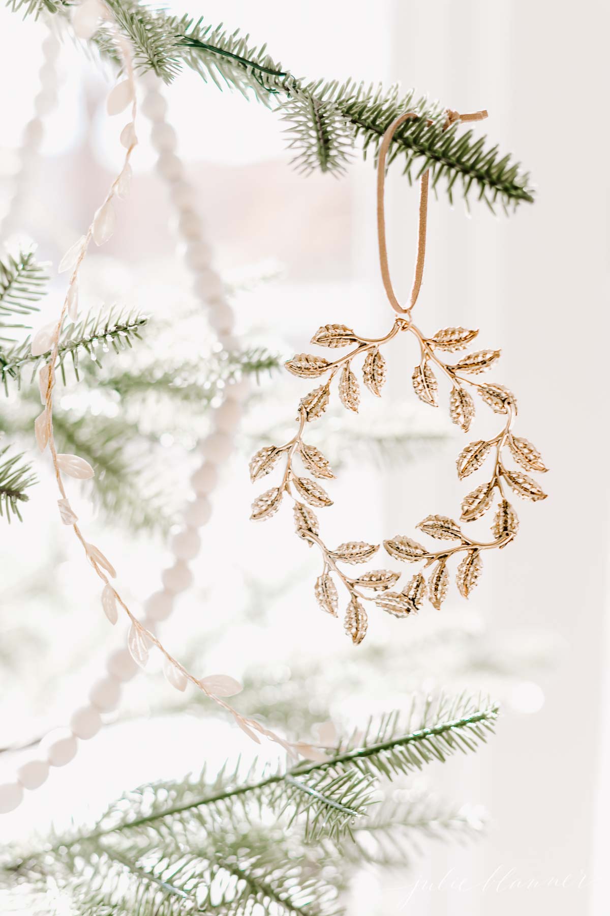 A gold laurel wreath ornament hangs on a Christmas tree.