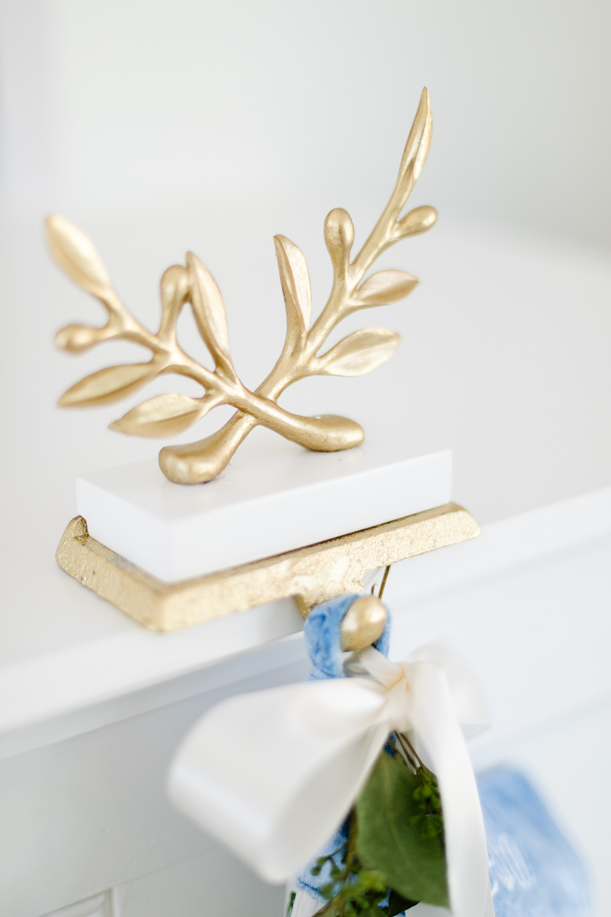A blue and gold stocking holder adorned with a laurel wreath on a dresser.