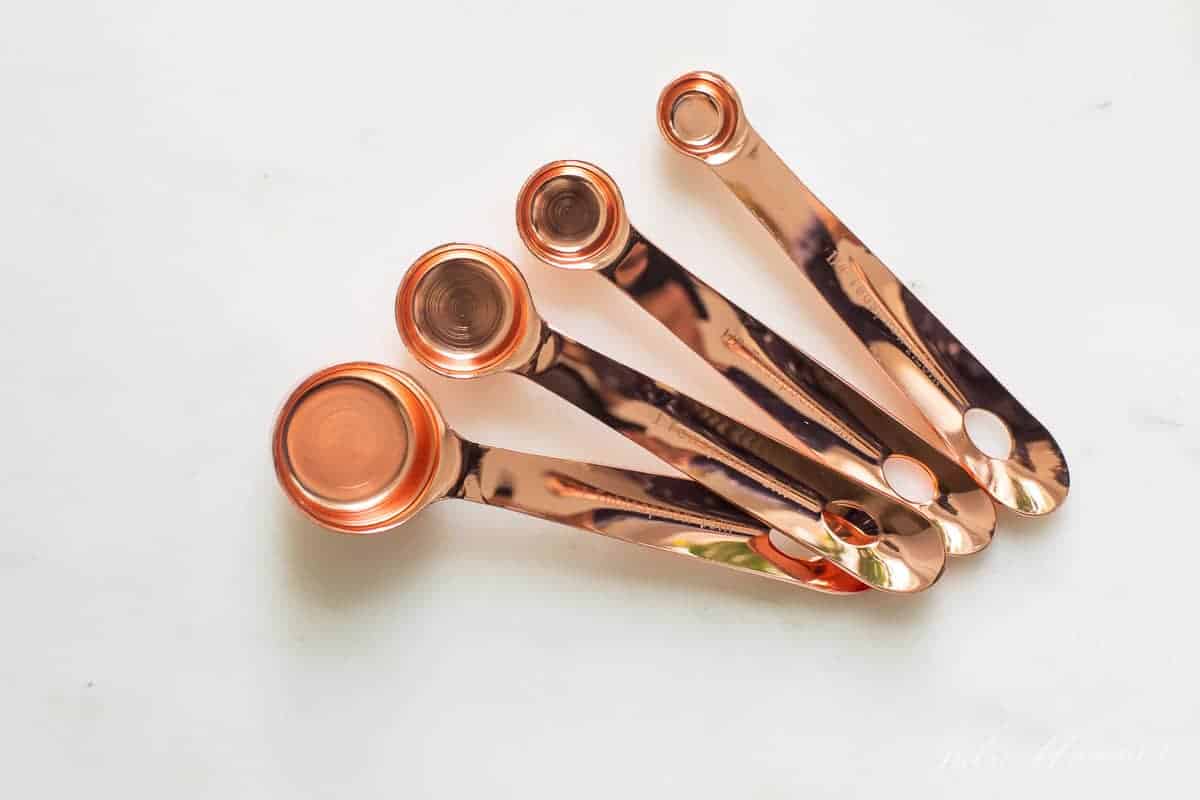 copper measuring spoons on marble surface
