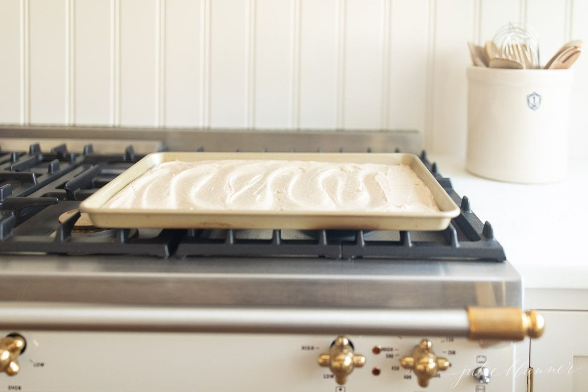 A sheet pan prepped for baking a cake, resting on top of a French range.
