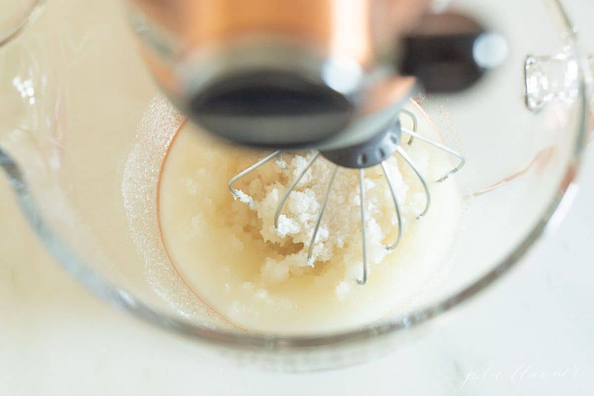Looking down inside a fitted mixer bowl, mixing attachment and cake ingredients inside.