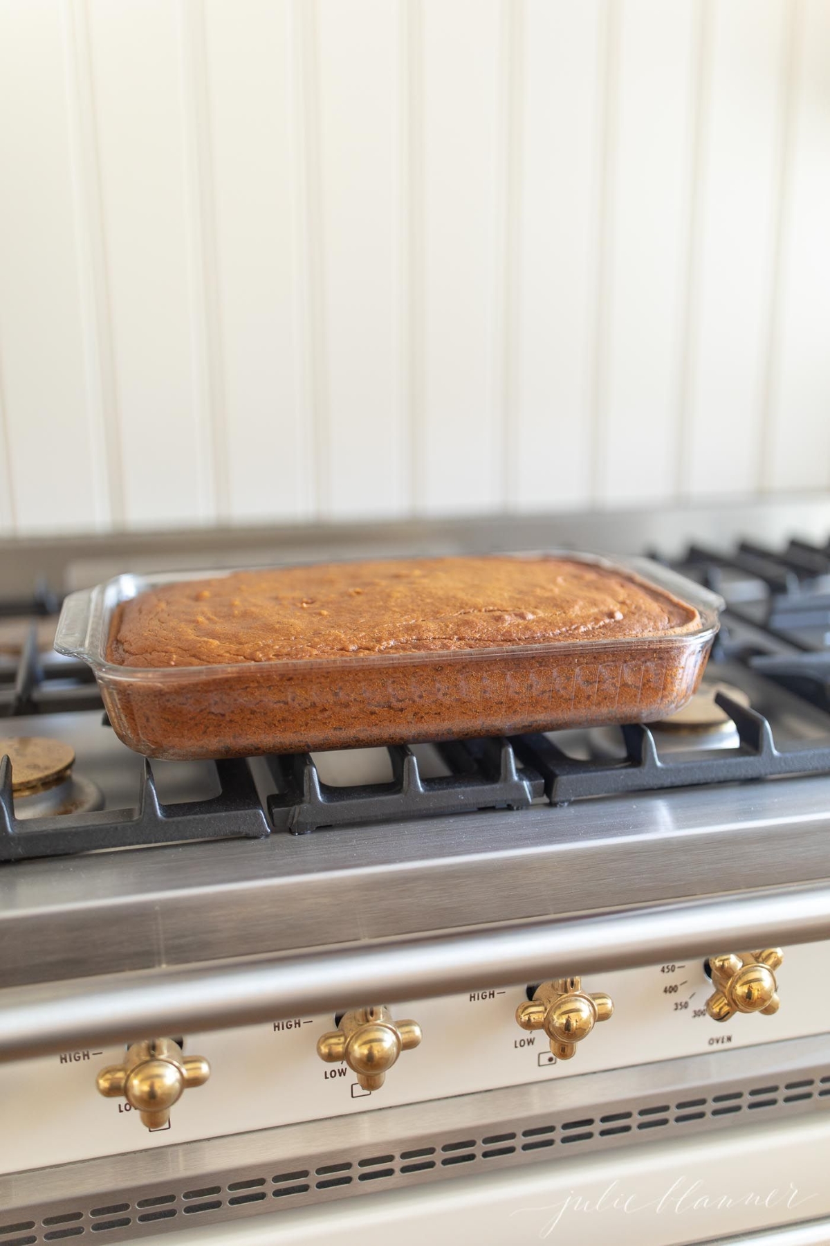 A pumpkin cake baked in a glass 9 by 13 inch baking pan, resting on top of a range.
