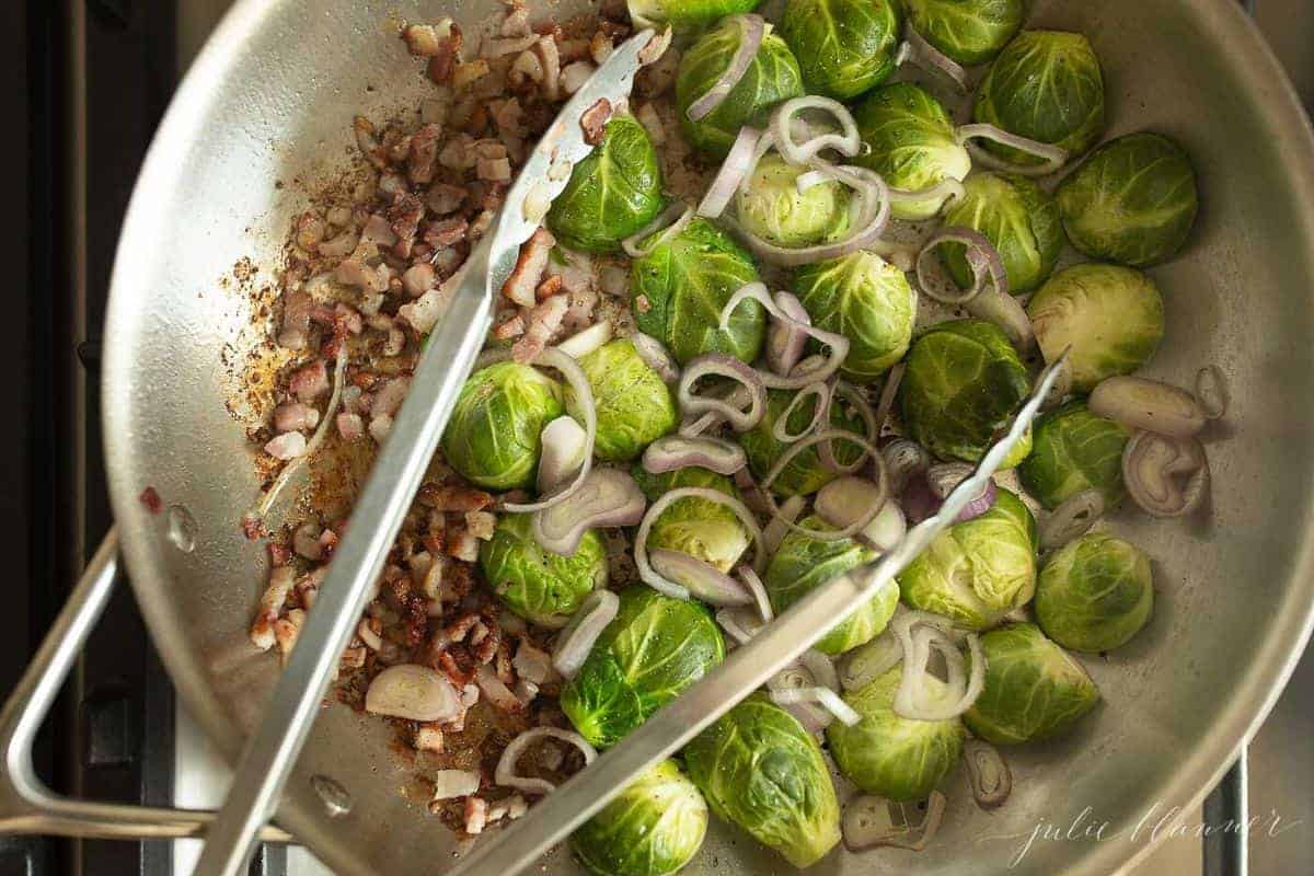 Crispy brussel sprouts ingredients in a pan, tongs in the center. 