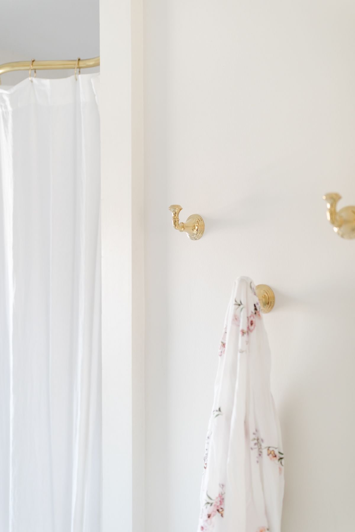 Gold robe hooks on the wall of a white spa bath