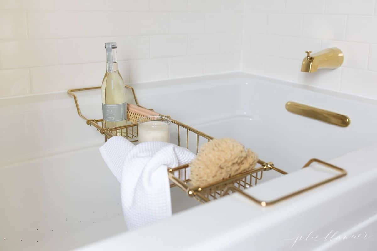 Air tub with brass bath fittings and a brass bath tray filled with bath goods.