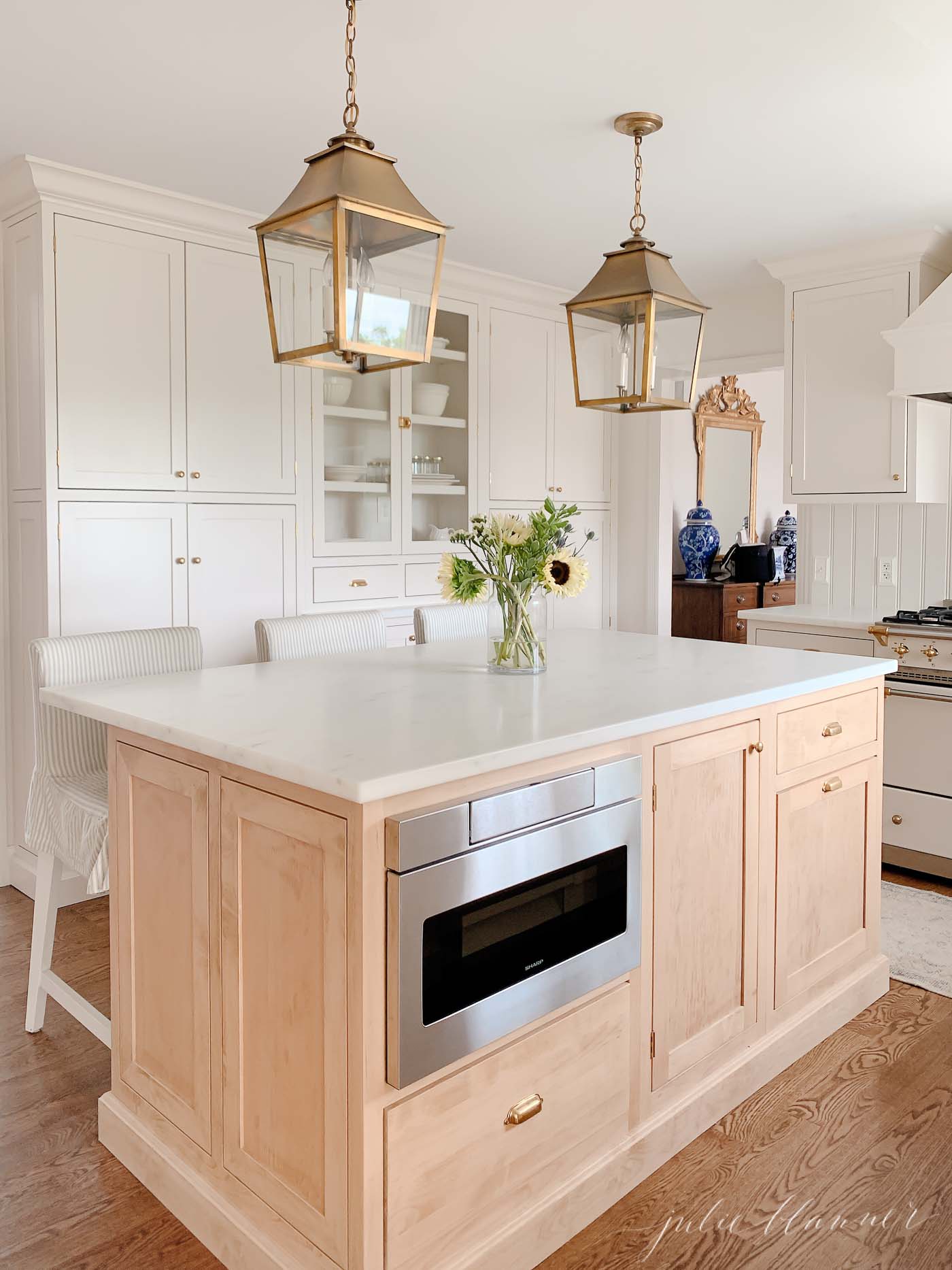 A cream kitchen fitted with custom cabinetry and a white oak custom kitchen cabinet island. 