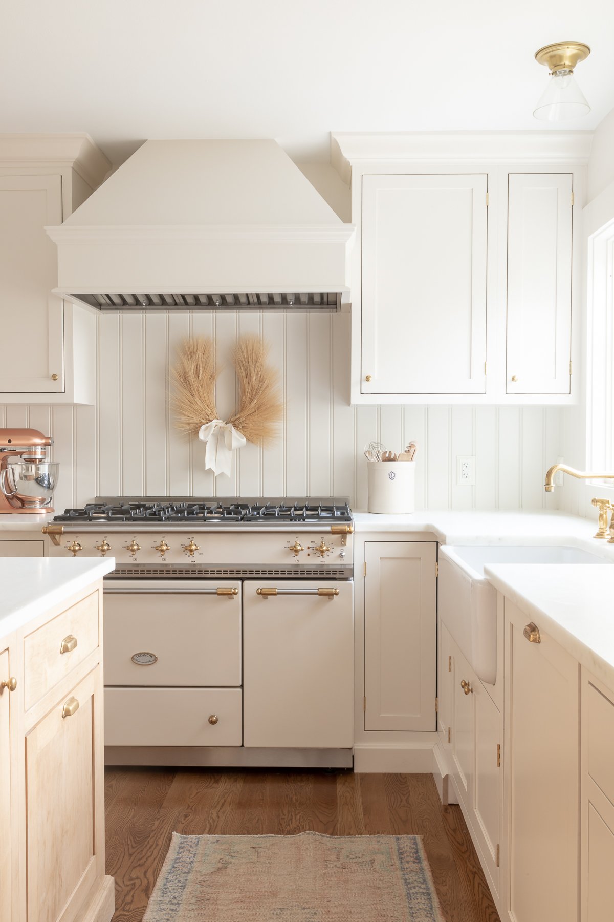 A kitchen with white cabinets and gold laurel wreaths accents.