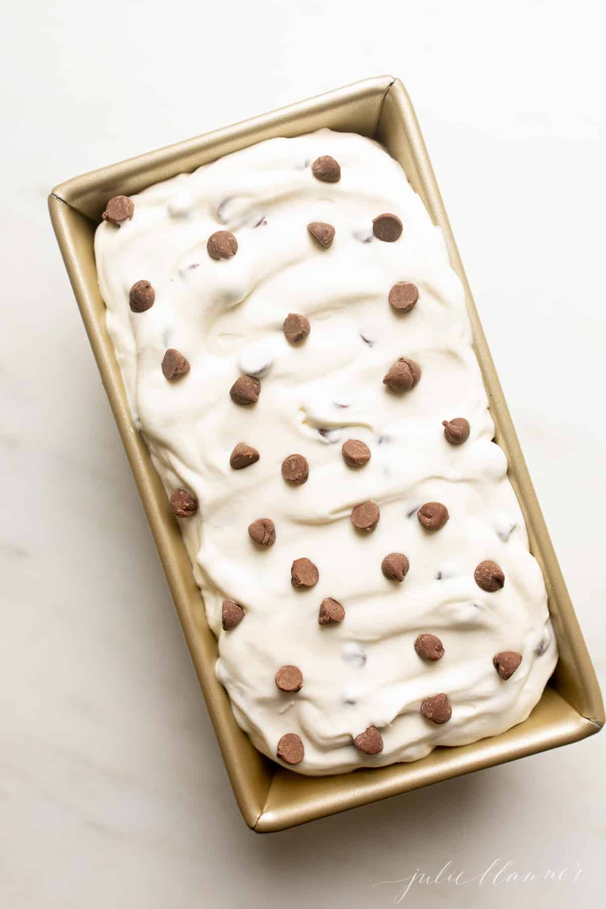 Chocolate chip ice cream in a tin on a marble work surface