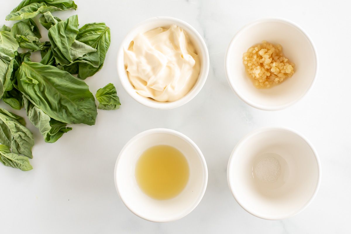 Ingredients for basil aioli laid out on a marble surface.