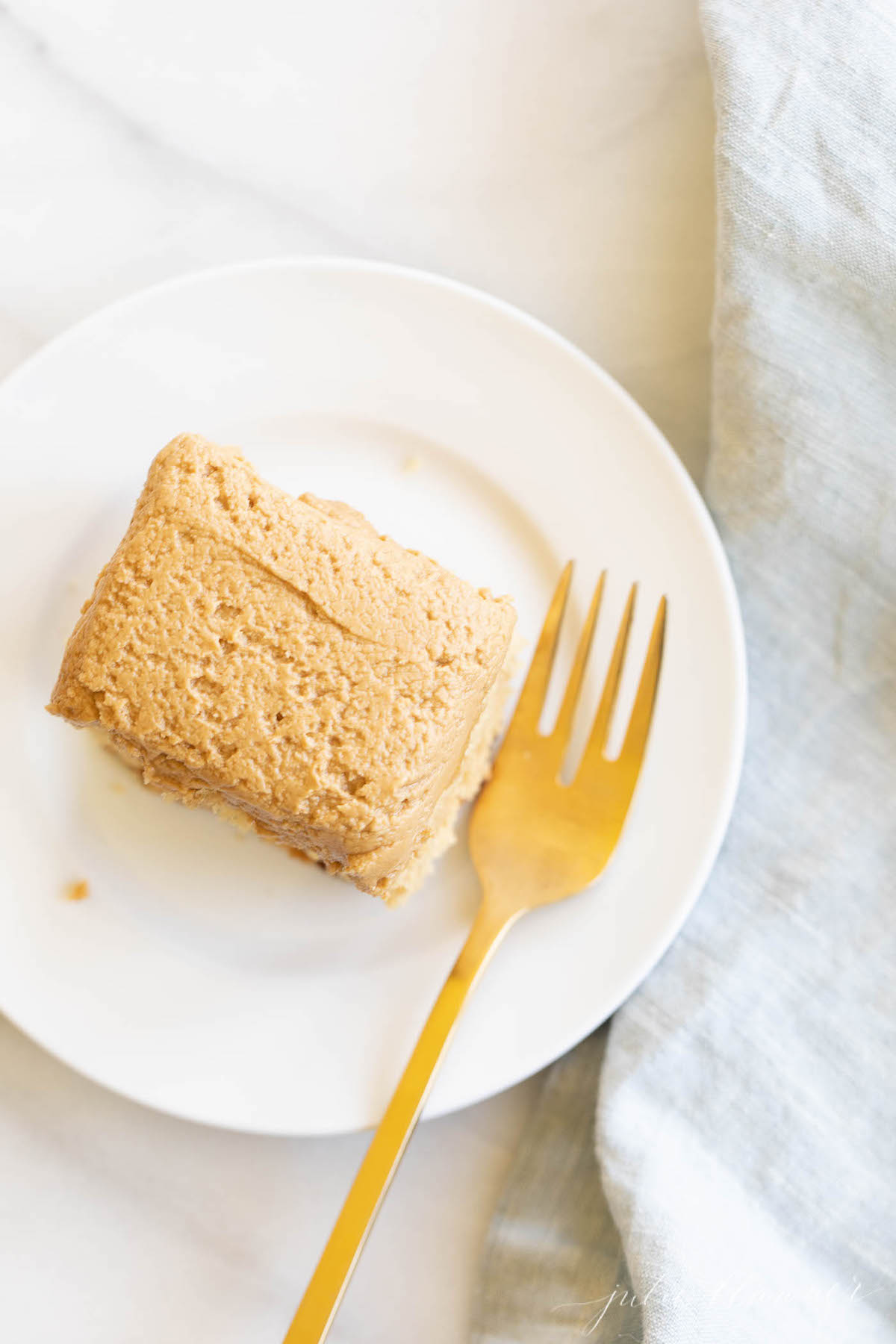 A slice of a Biscoff cake recipe on a plate with a gold fork.