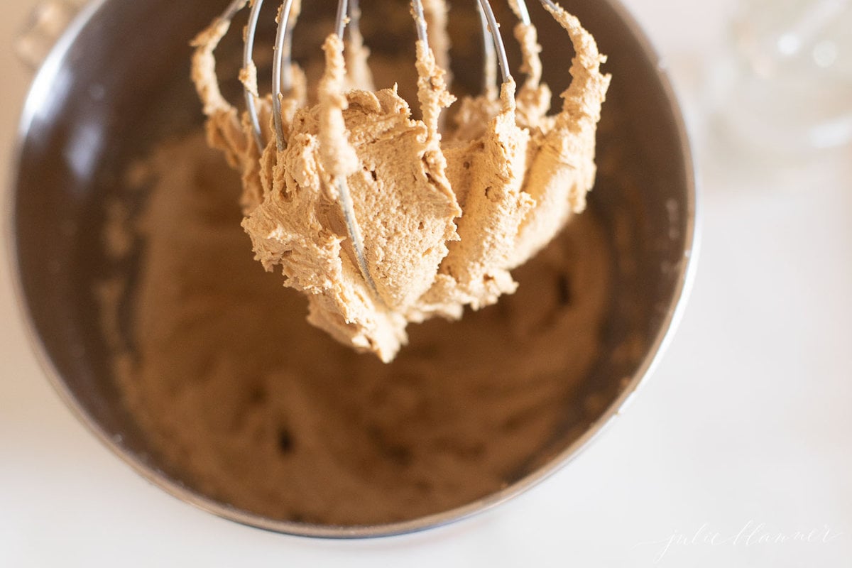 A metal mixing bowl with a whisk in it, used for preparing speculoos cake.
