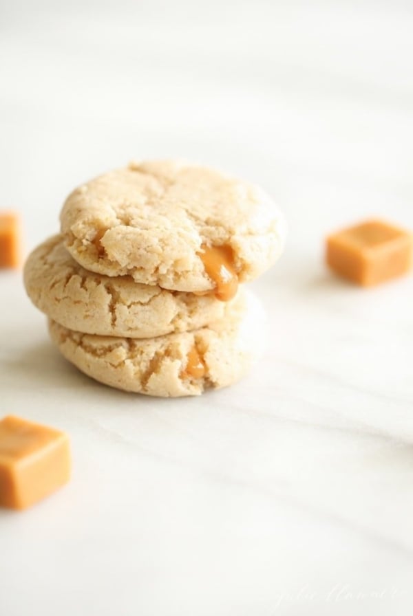 A stack of caramel stuffed cheesecake cookies on a marble countertop.