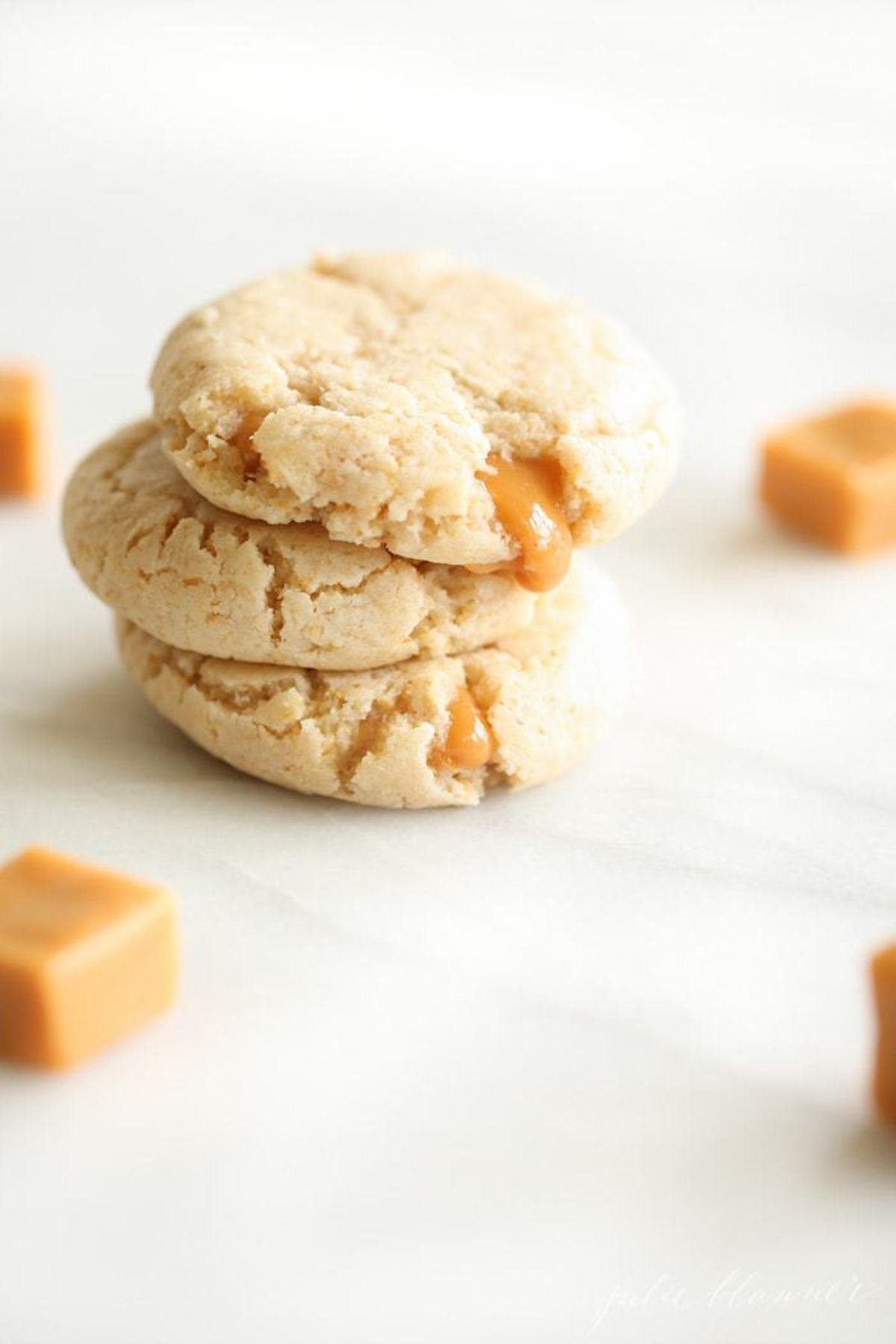 A stack of caramel stuffed cheesecake cookies on a marble countertop. 