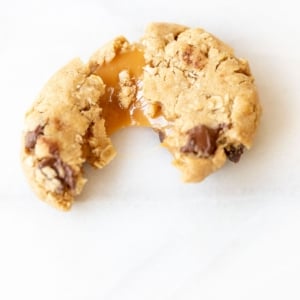 A carmelita cookie on a white marble surface, torn into two pieces.