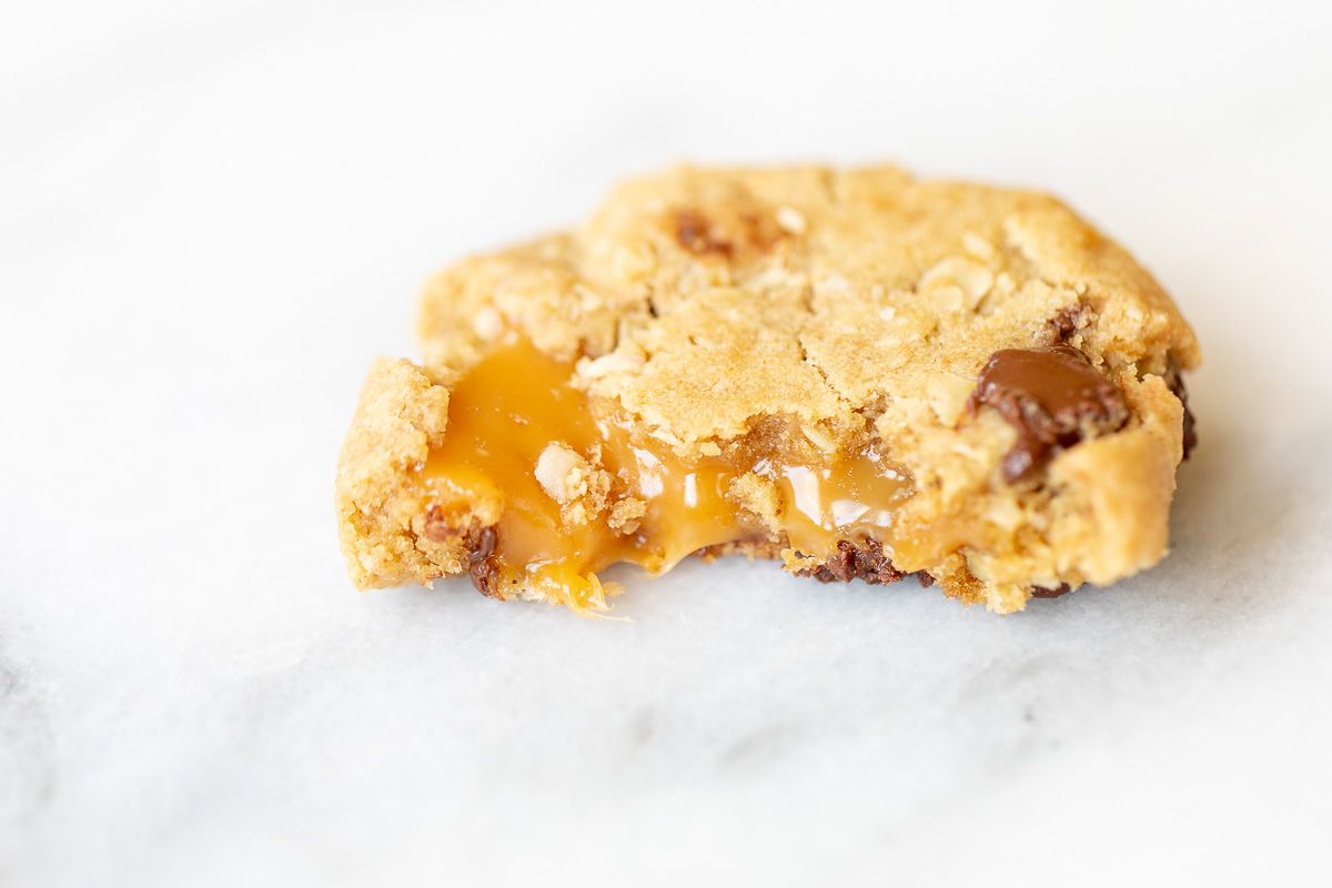 A carmelita cookie on a white marble surface, torn into two pieces.