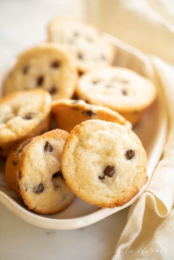 A white platter full of mini chocolate chip muffins.