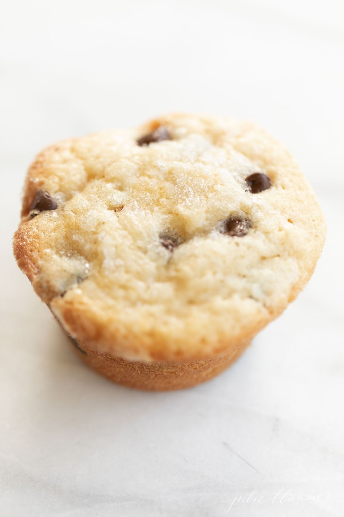 A chocolate chip muffin on a marble surface.