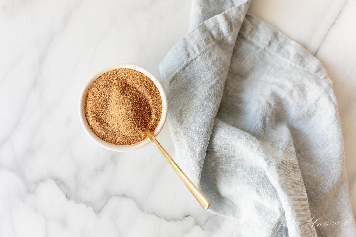 A bowl of cinnamon sugar with a gold spoon.