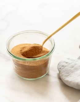 A bowl of cinnamon sugar with a gold spoon.