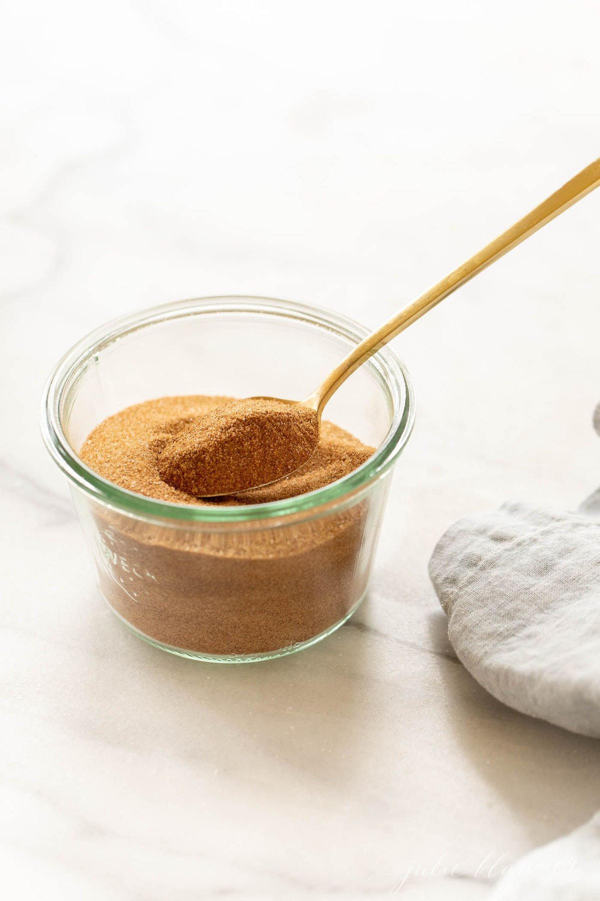 A bowl of cinnamon sugar with a gold spoon.