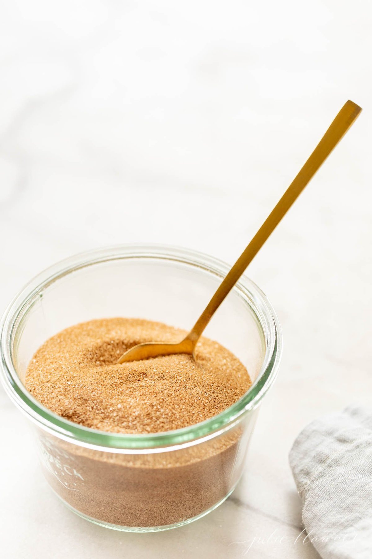 A bowl of cinnamon sugar with a gold spoon.