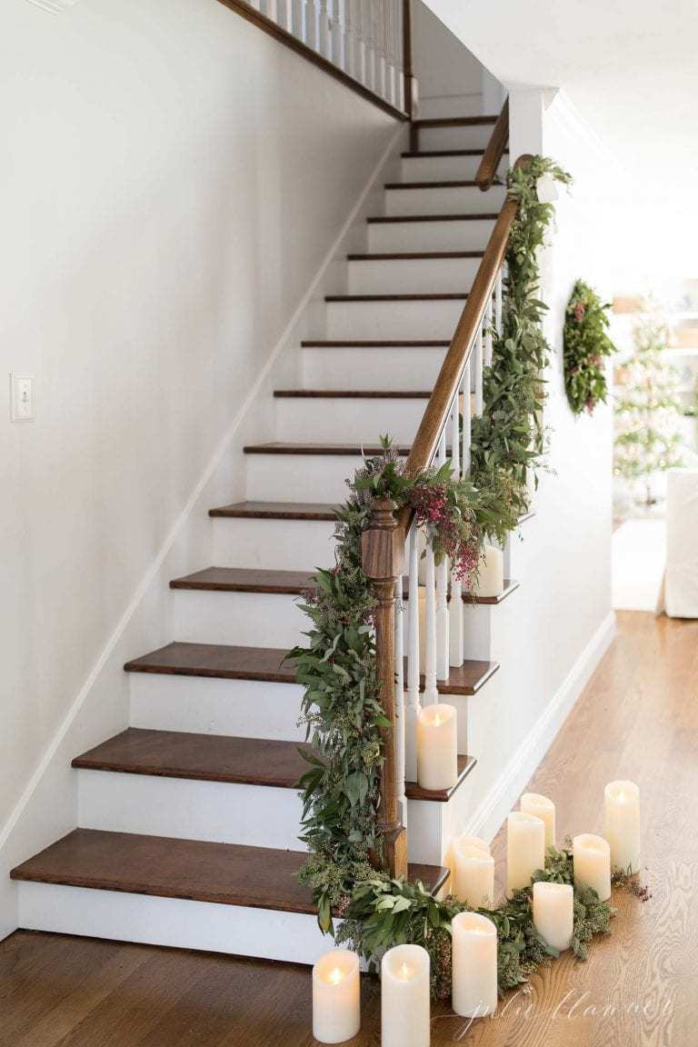 A wooden staircase decorated with candles and garland for Christmas.