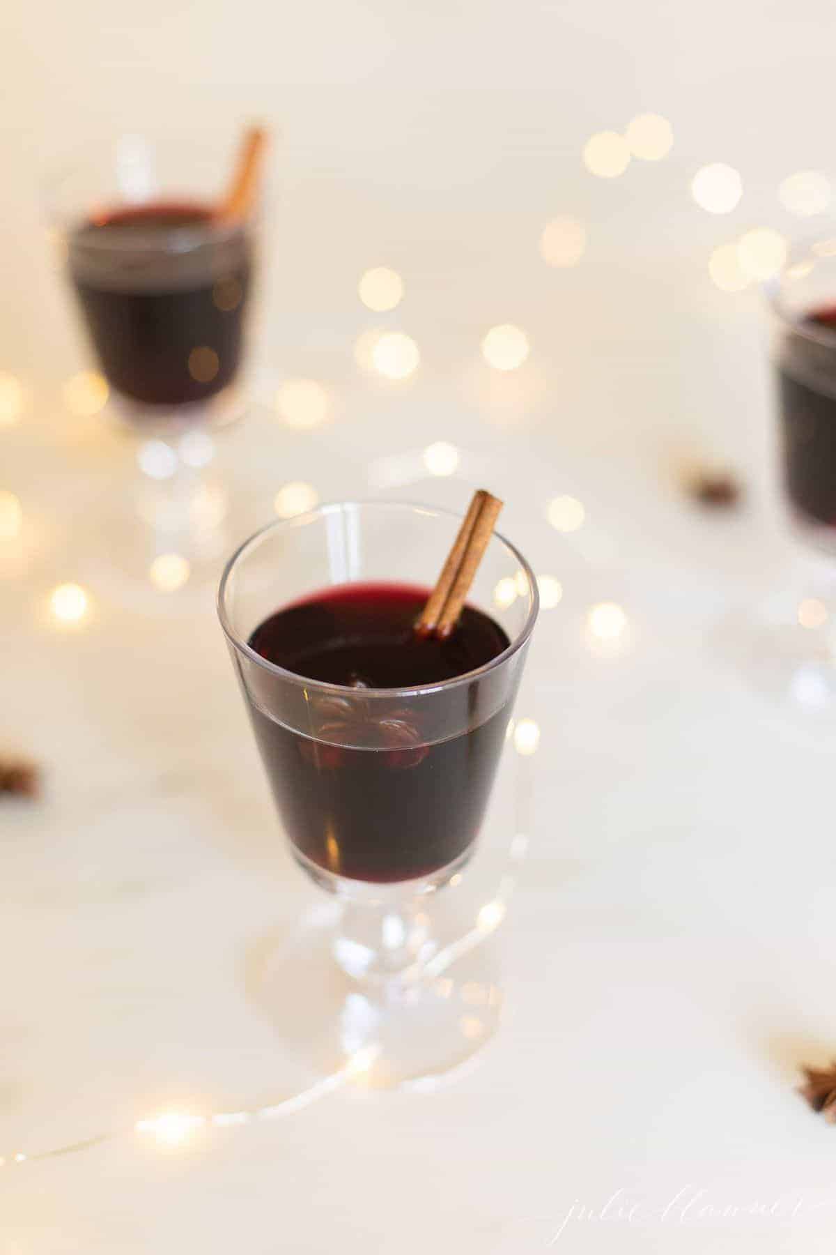 Glasses full of a gluhwein recipe, sparkling lights scattered around.