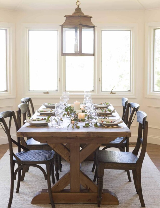 Farm table set for Thanksgiving dinner, candles and branches down the center.