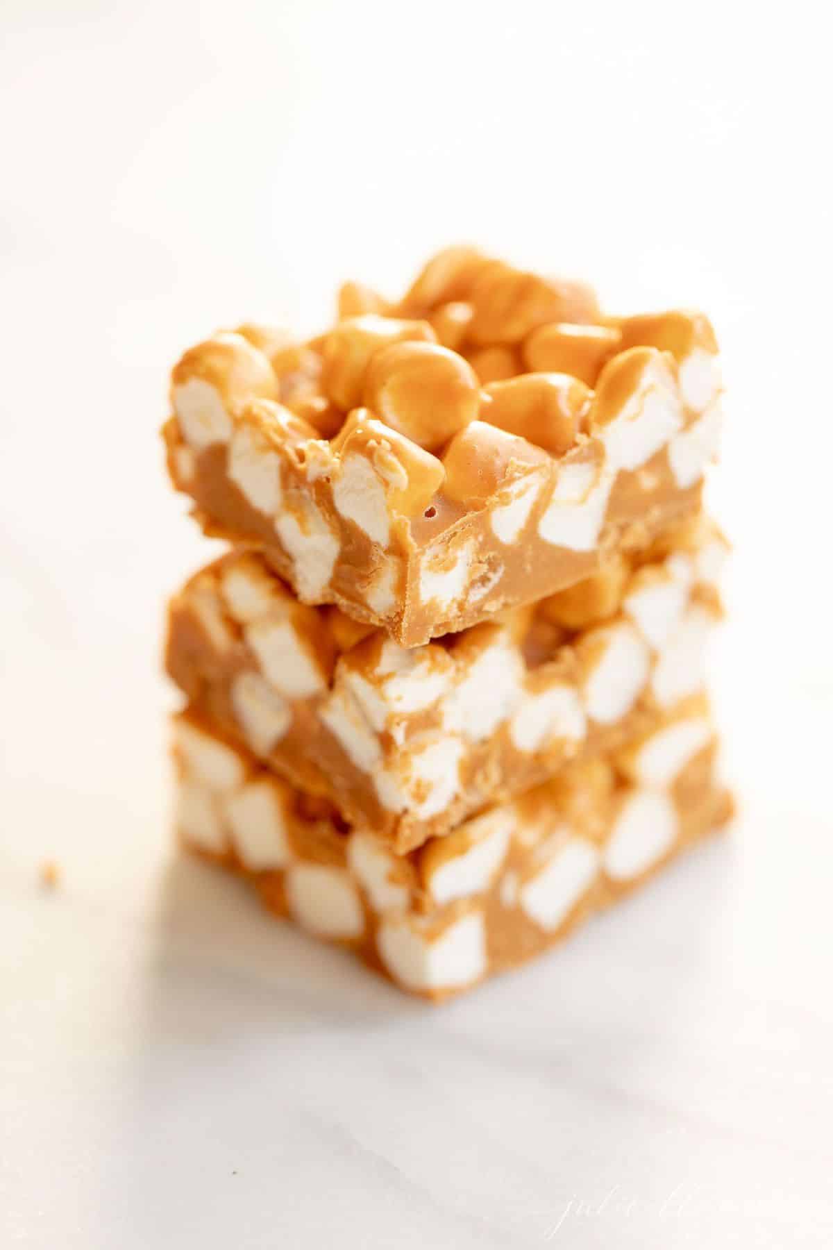 Stack of three homemade no bake butterscotch candy bars on a marble surface.