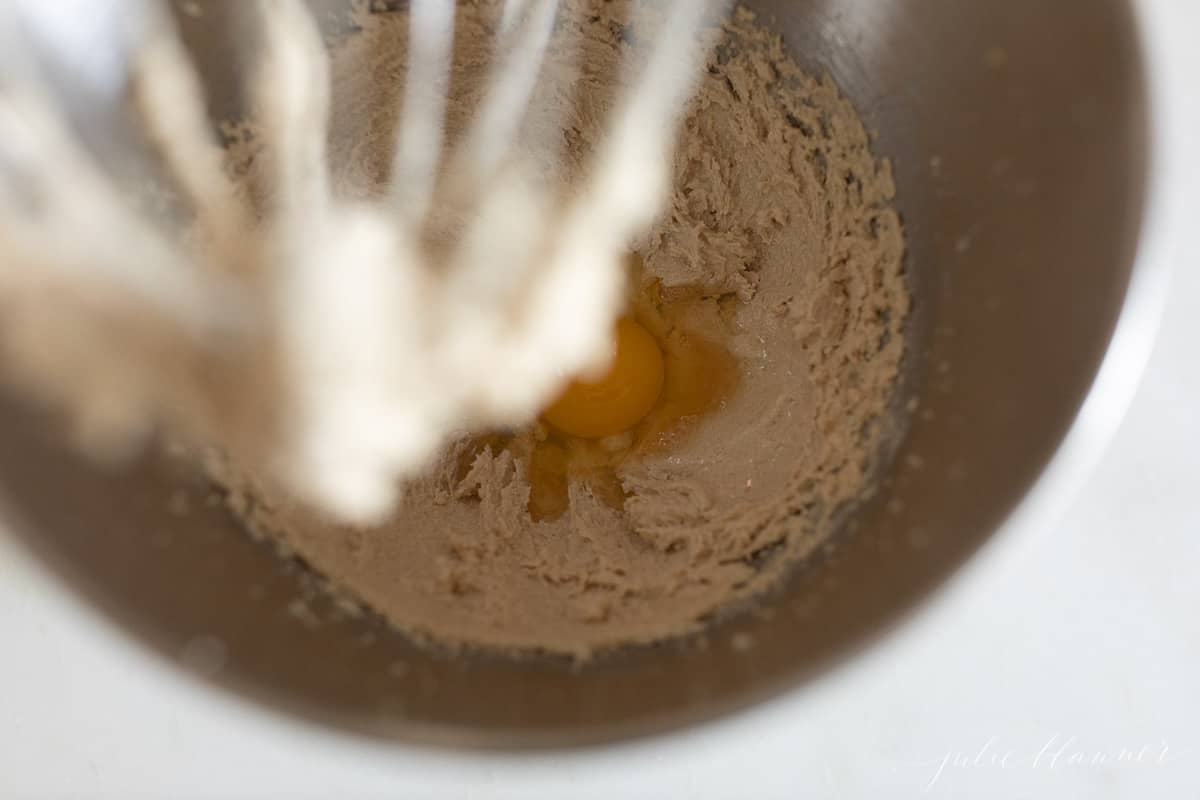 Looking inside a mixing bowl, cookie dough with egg on top.