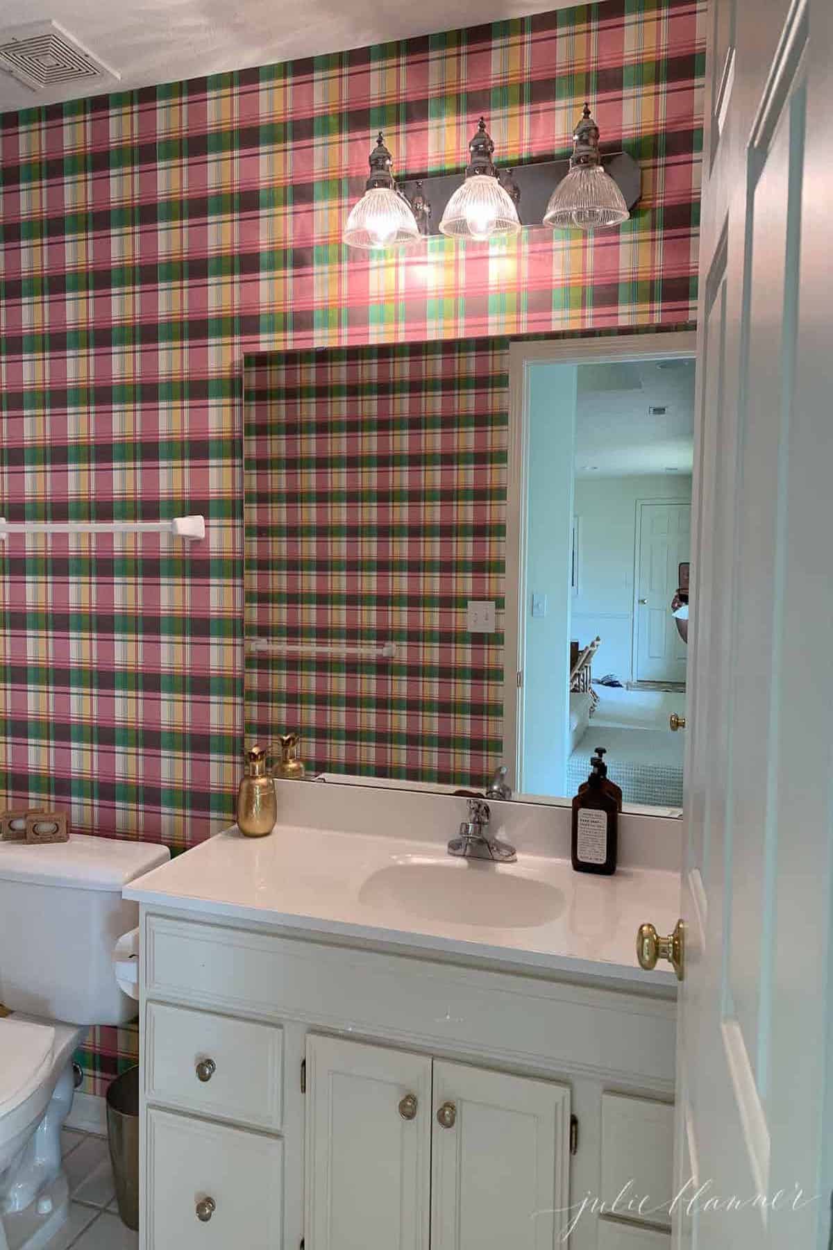 A bathroom with a nautical-themed pink and white checkered wallpaper.