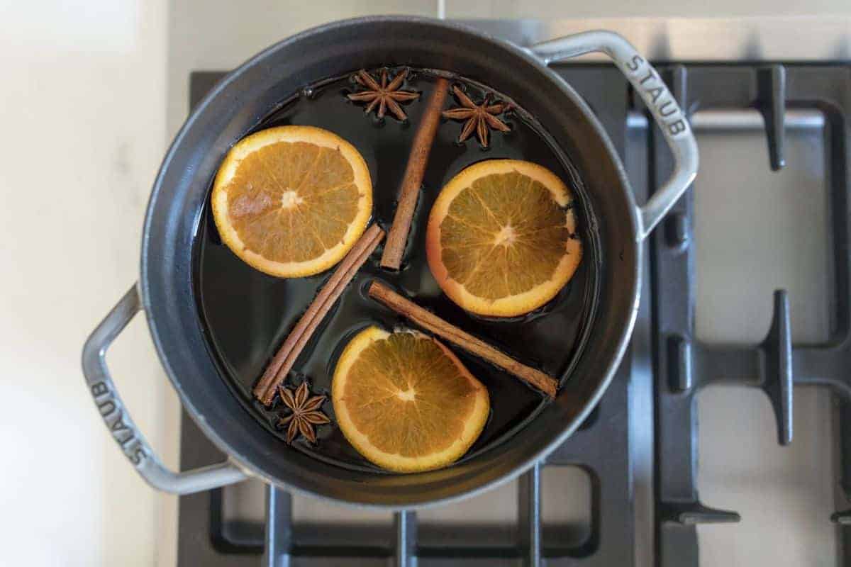 Gray enameled cast iron pot on stove top with mulled wine inside.