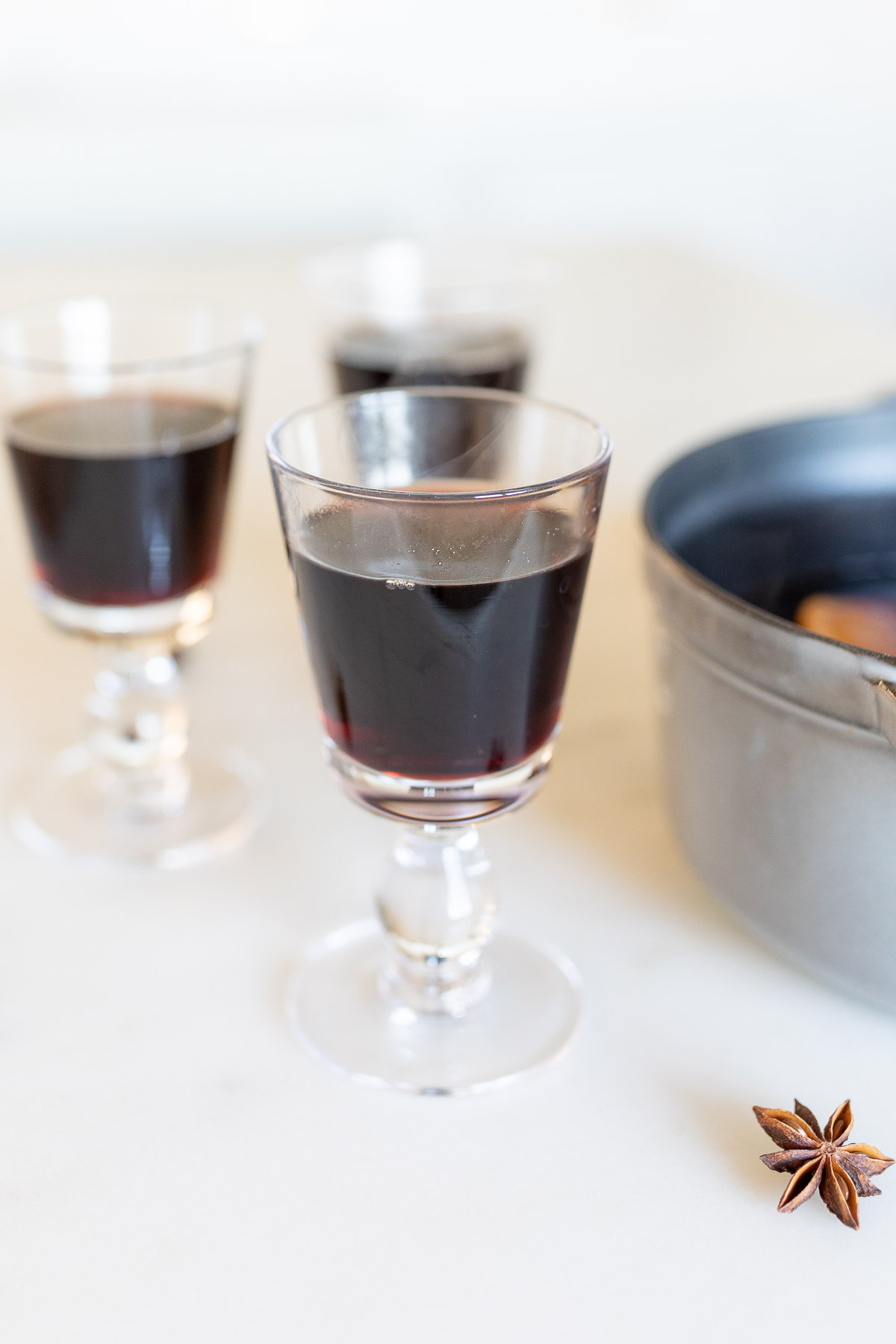 Mulled wine in a cast iron pot, surrounded by glasses of mulled wine.