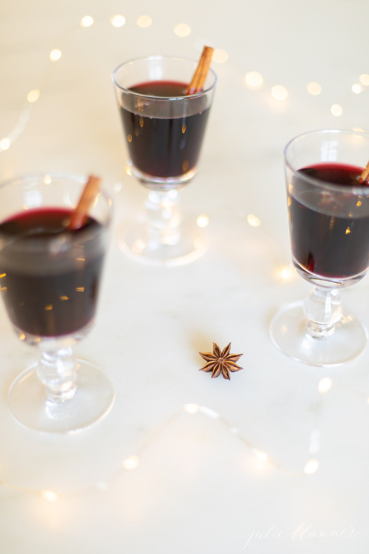 Glasses of mulled wine garnished with cinnamon sticks.