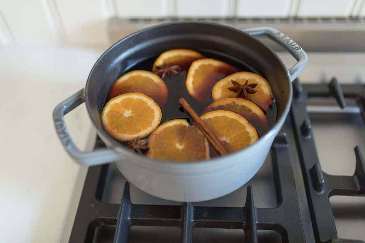 A gray cast iron pot on a stove top full of mulled wine.