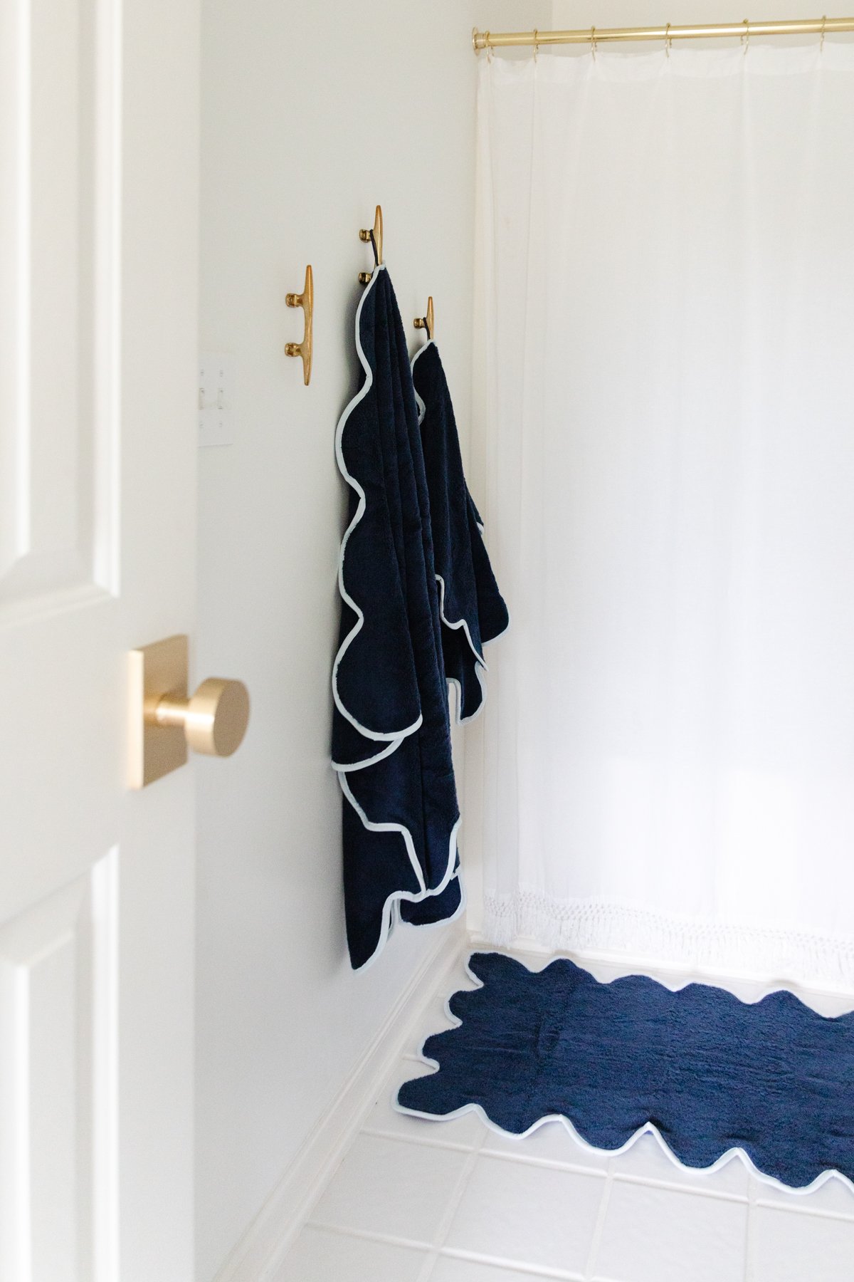 A nautical-themed bathroom with a white shower curtain and a blue rug.