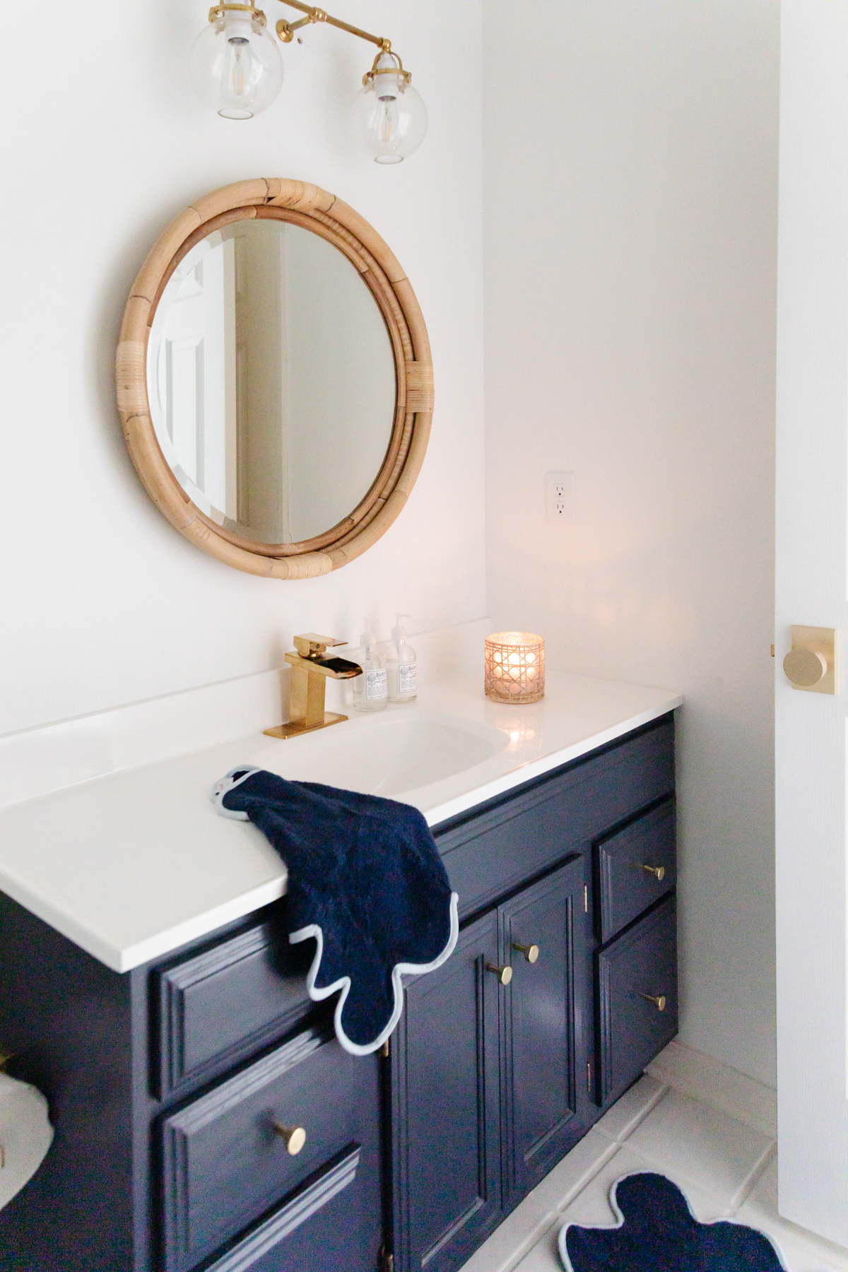 A nautical-themed bathroom with a blue rug and a round mirror.
