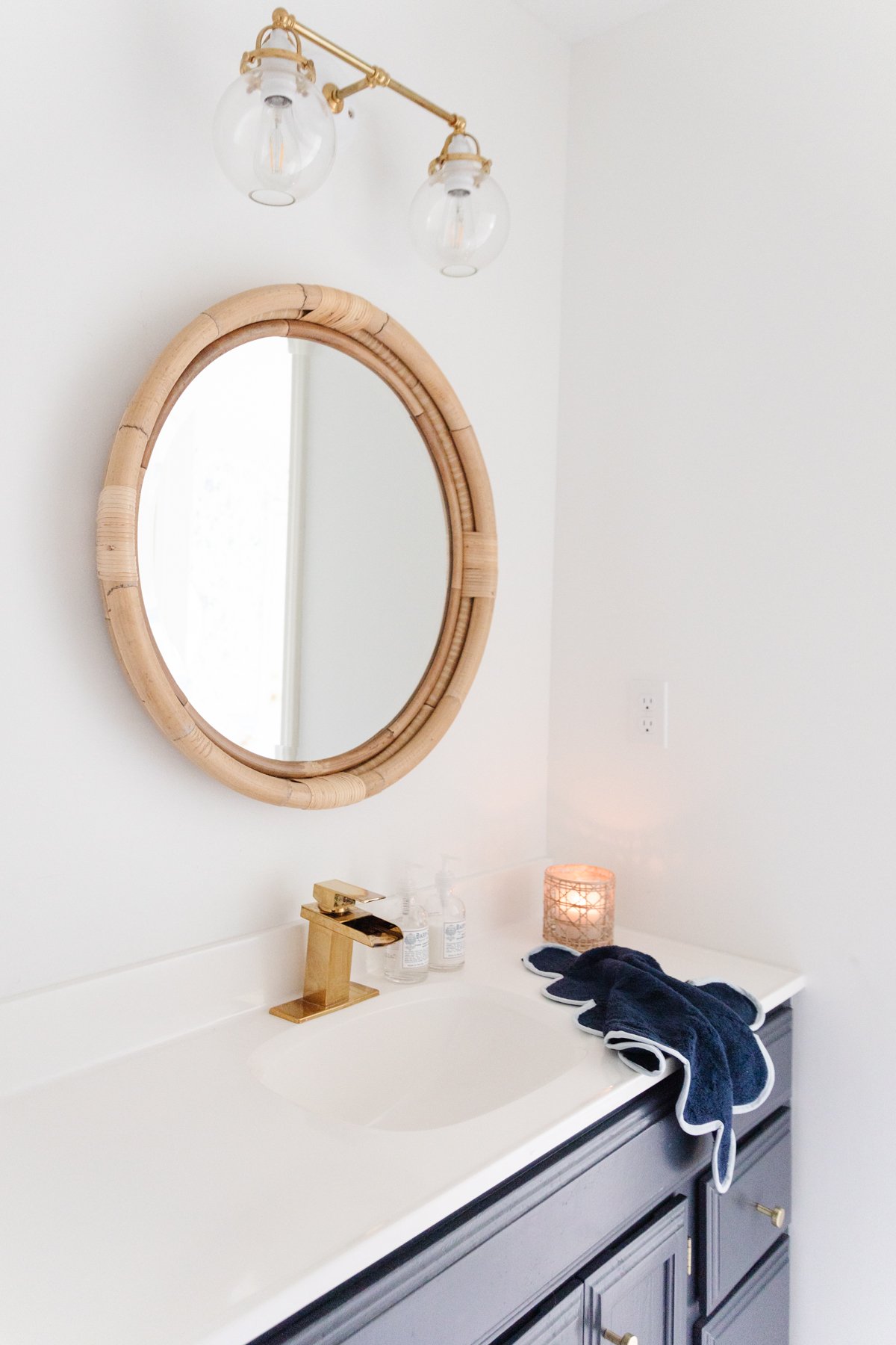 A nautical-themed bathroom vanity with a round mirror and blue towels.
