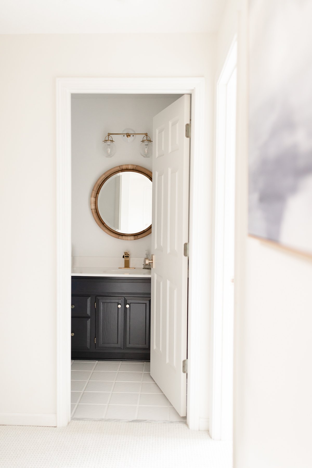 A white bathroom with a navy vanity and white tile floors with white grout paint.