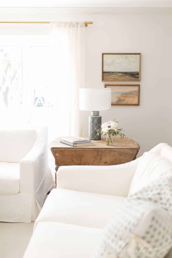 A living room with white sofas and a wooden side table