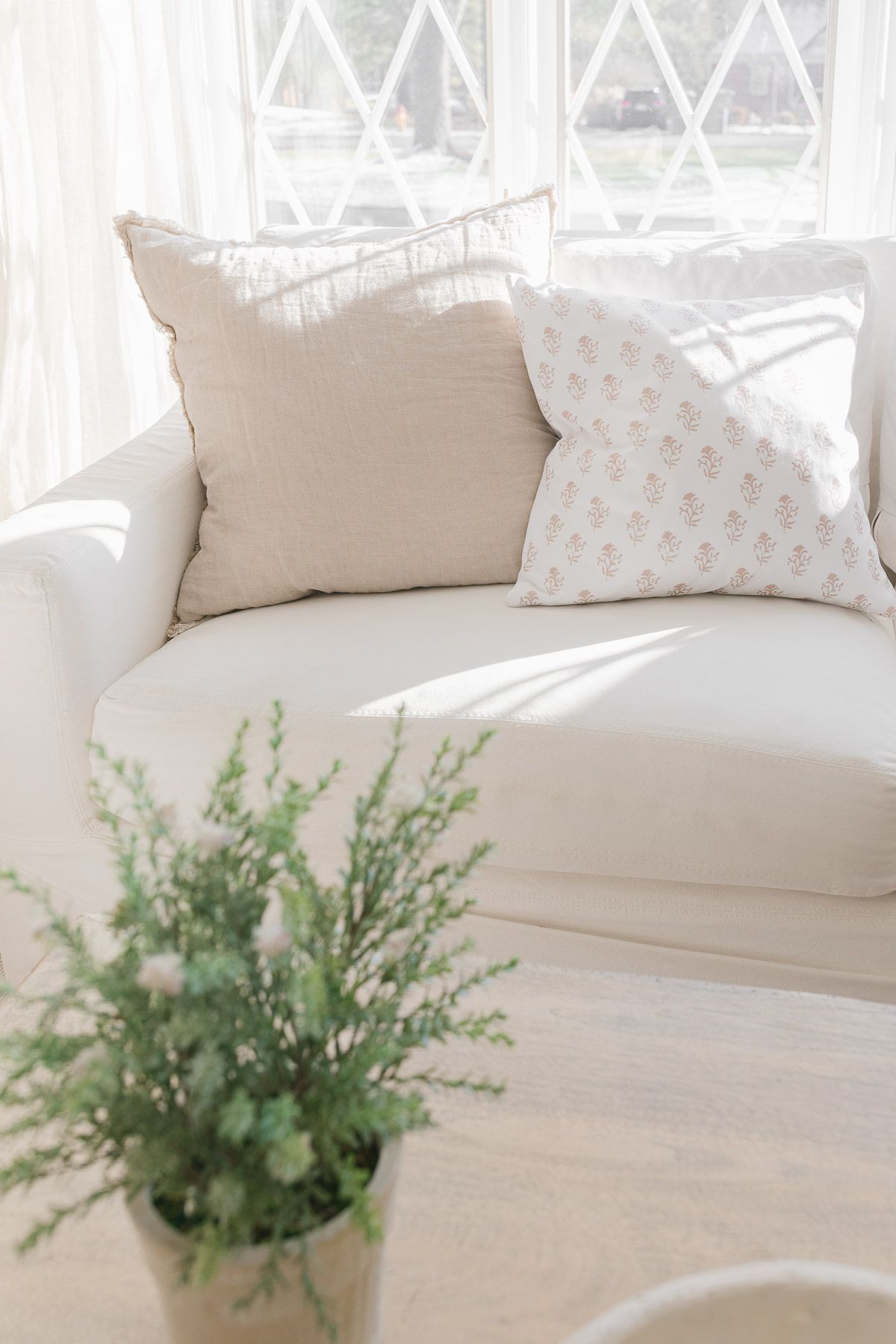 Soft pastel pillows piled on a white Pottery Barn slipcovered sofa