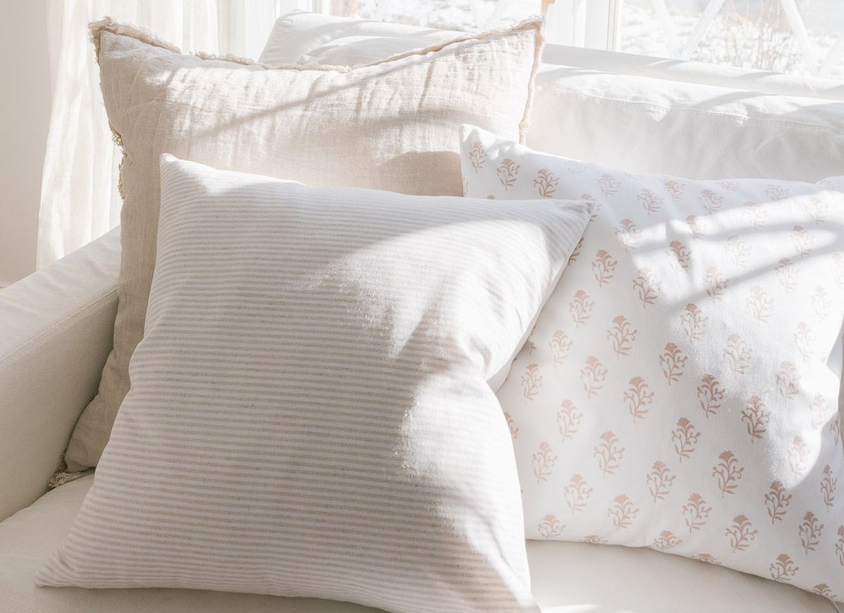 Soft pastel pillows piled on a white Pottery Barn slipcovered sofa