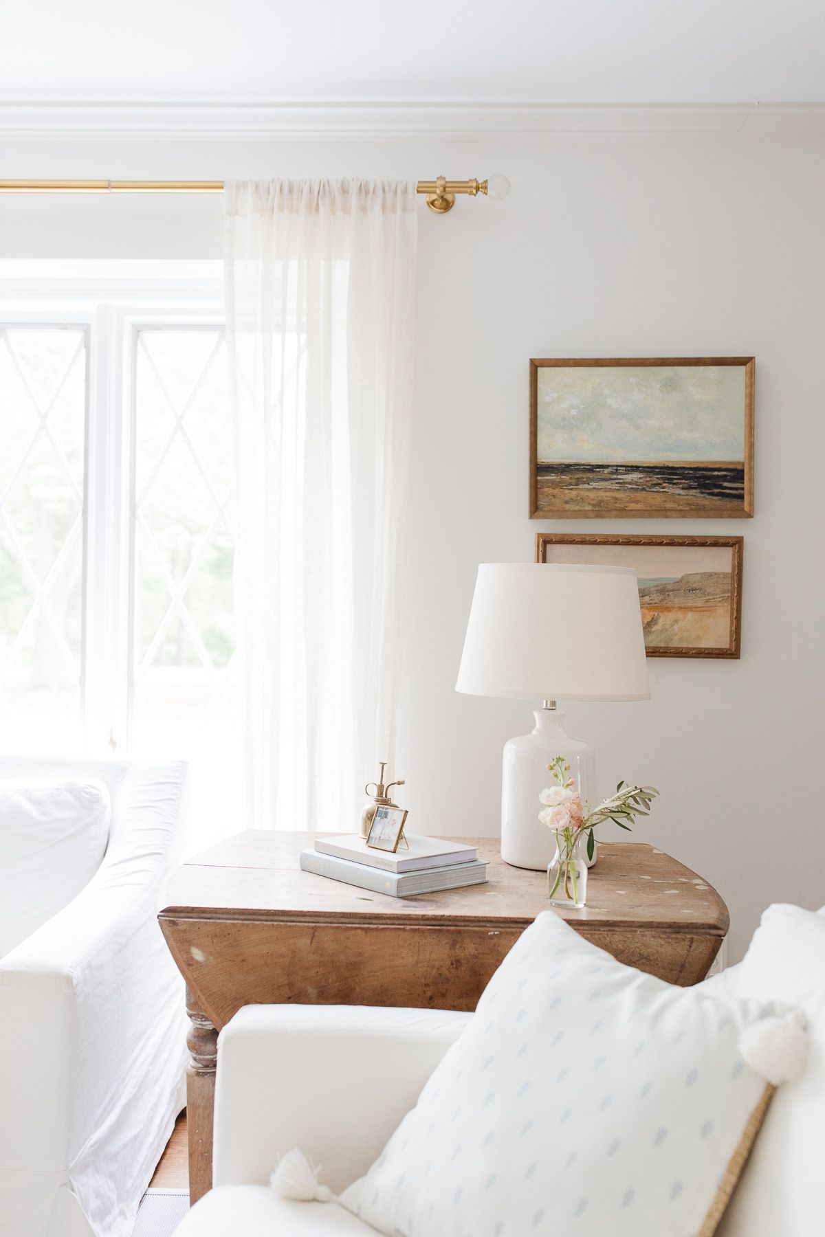 Two white Pottery Barn sofas with a wooden end table in a neutral living room