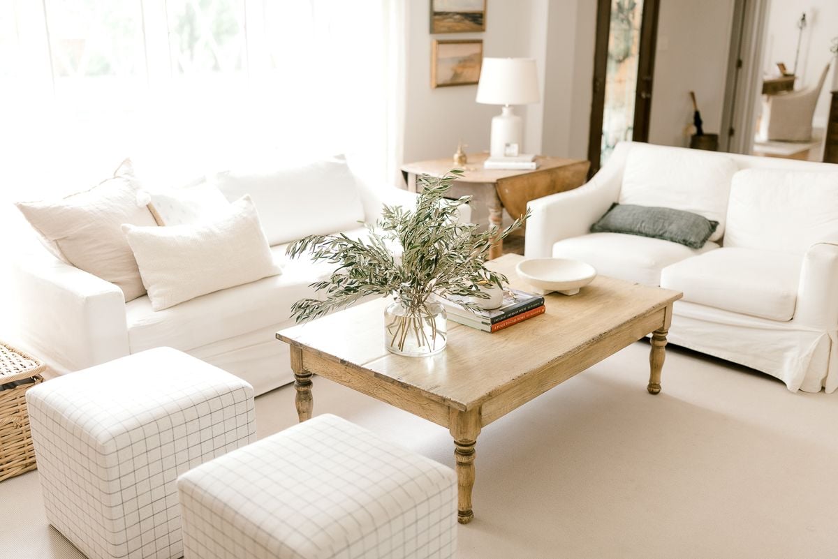 Two white Pottery Barn sofas with a wooden coffee table in a neutral living room