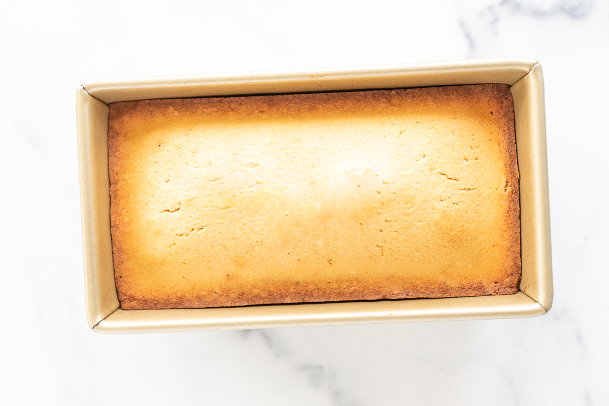 A loaf of pound cake in a box on a marble surface.